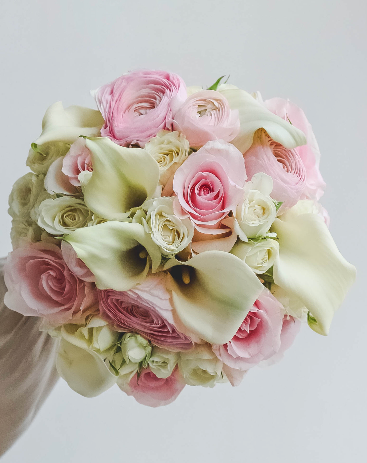 Ein Brautstrauß aus Calla-Lilien und Ranunkeln in Pink und Weiß