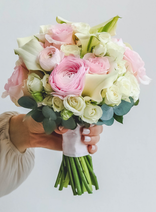 Ein Brautstrauß aus Calla-Lilien und Ranunkeln in Pink und Weiß